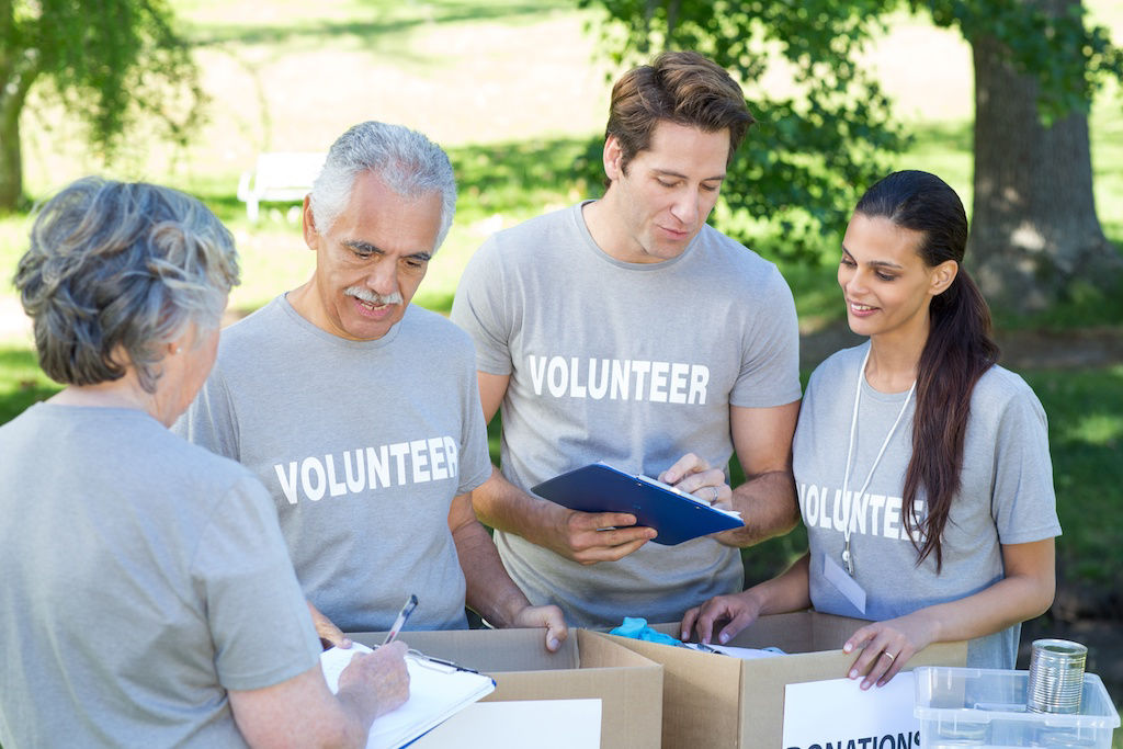 Two senior citizens and two younger adults packing boxes while volunteering